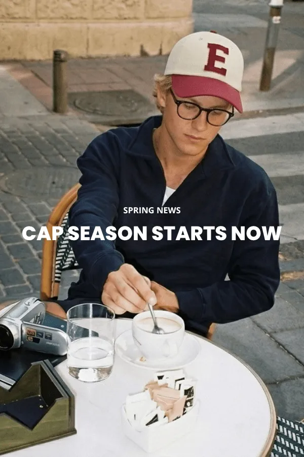 Mężczyzna siedzi na drewnianej skrzynce w studiu i nosi klasyczny brązowy kapelusz kowbojski z filcu z szerokim rondem, ciemną dżinsową koszulę i dżinsy.